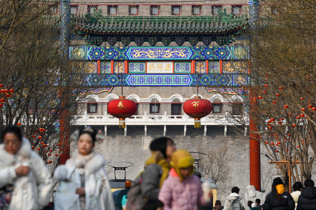 游客在前门大街参观游览，前门五牌楼上装饰有龙纹（2月5日摄）。新华社记者 鞠焕宗 摄